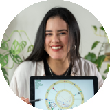 Smiling woman holding a laptop displaying a colorful astrological birth chart.