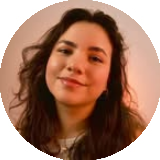 Smiling woman with long curly hair and natural makeup against a warm-toned background.